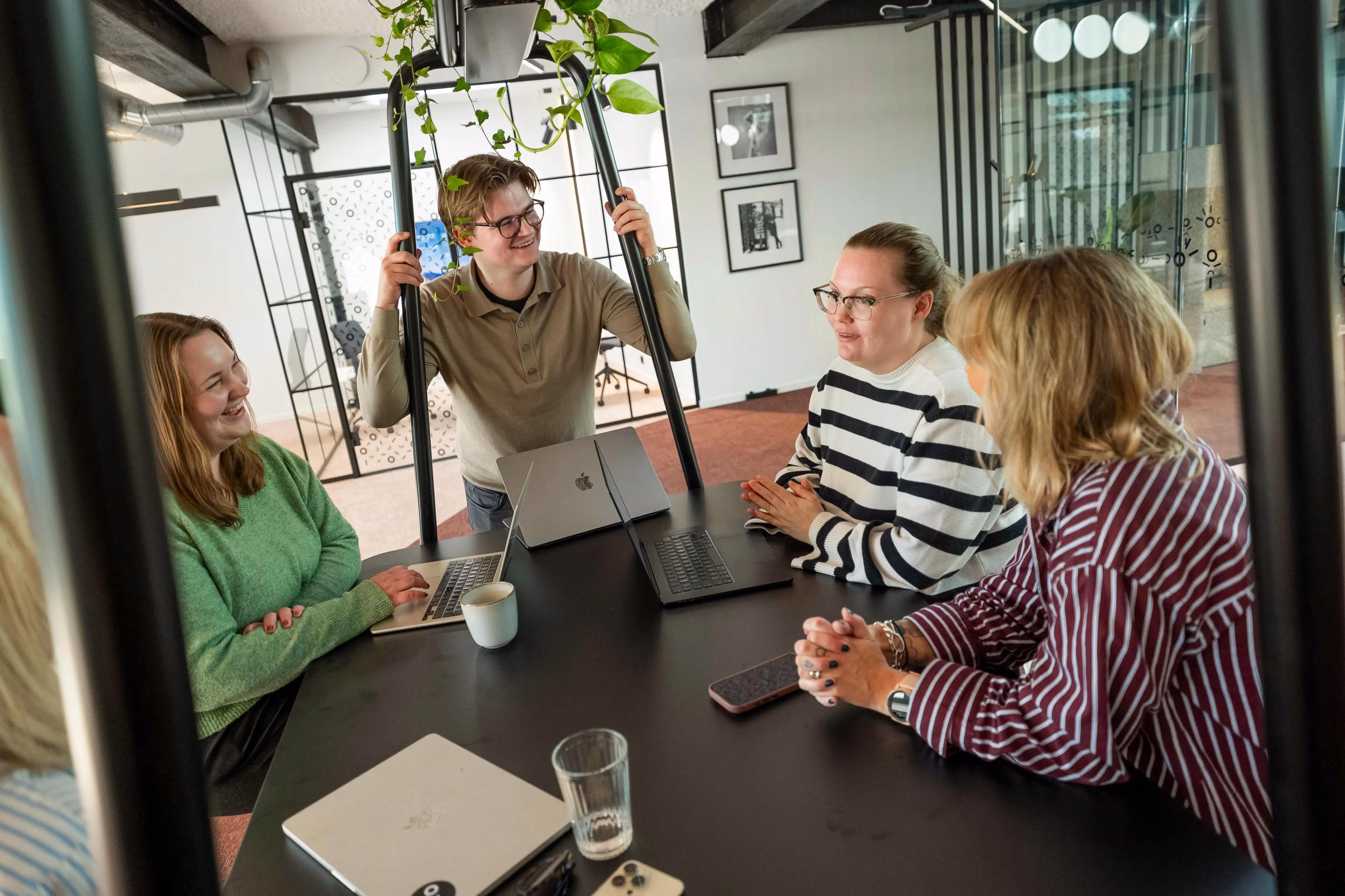 Fire kolleger i tur.digital som snakker sammen rundt et bord.